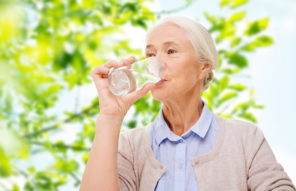 happy senior woman with glass of water at home